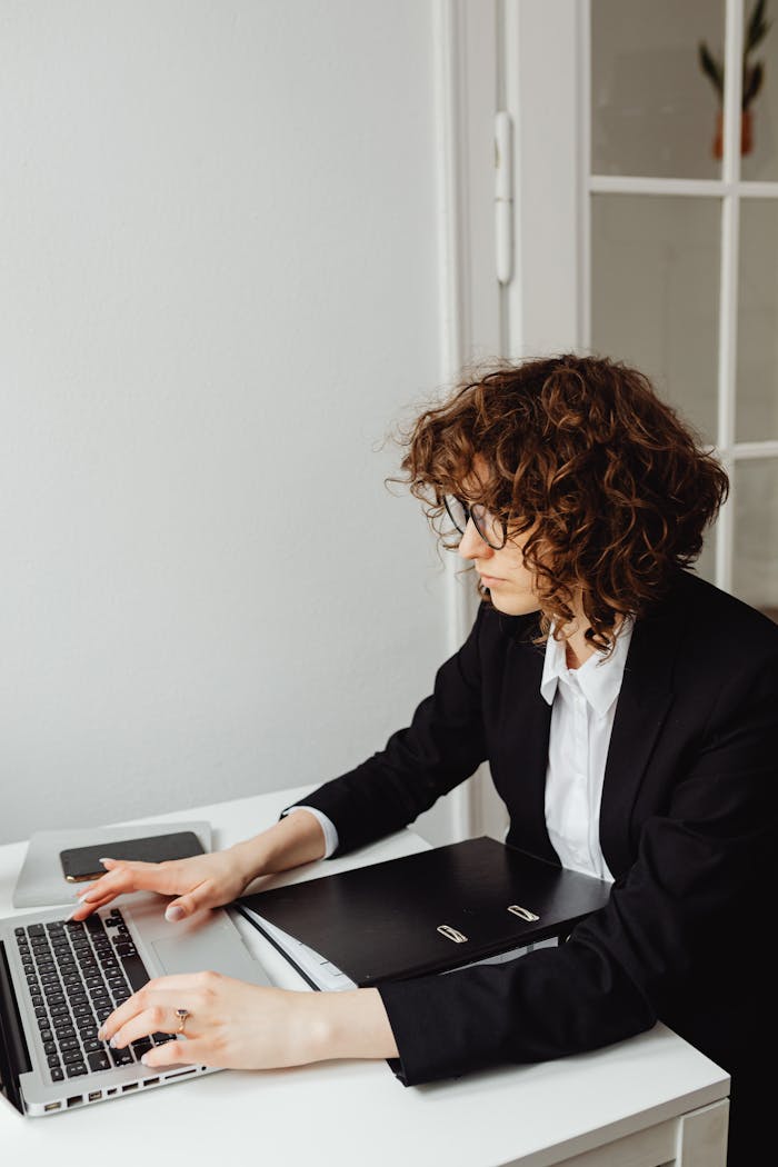 heros-img Woman in business attire working on a laptop in an office setting, focused on tasks.